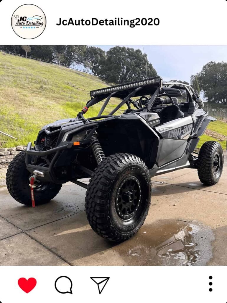 A gray Can-Am Maverick X3 off-road vehicle, recently detailed, parked on a driveway. The vehicle has large off-road tires, a light bar on the roof, and a winch mounted on the front bumper.