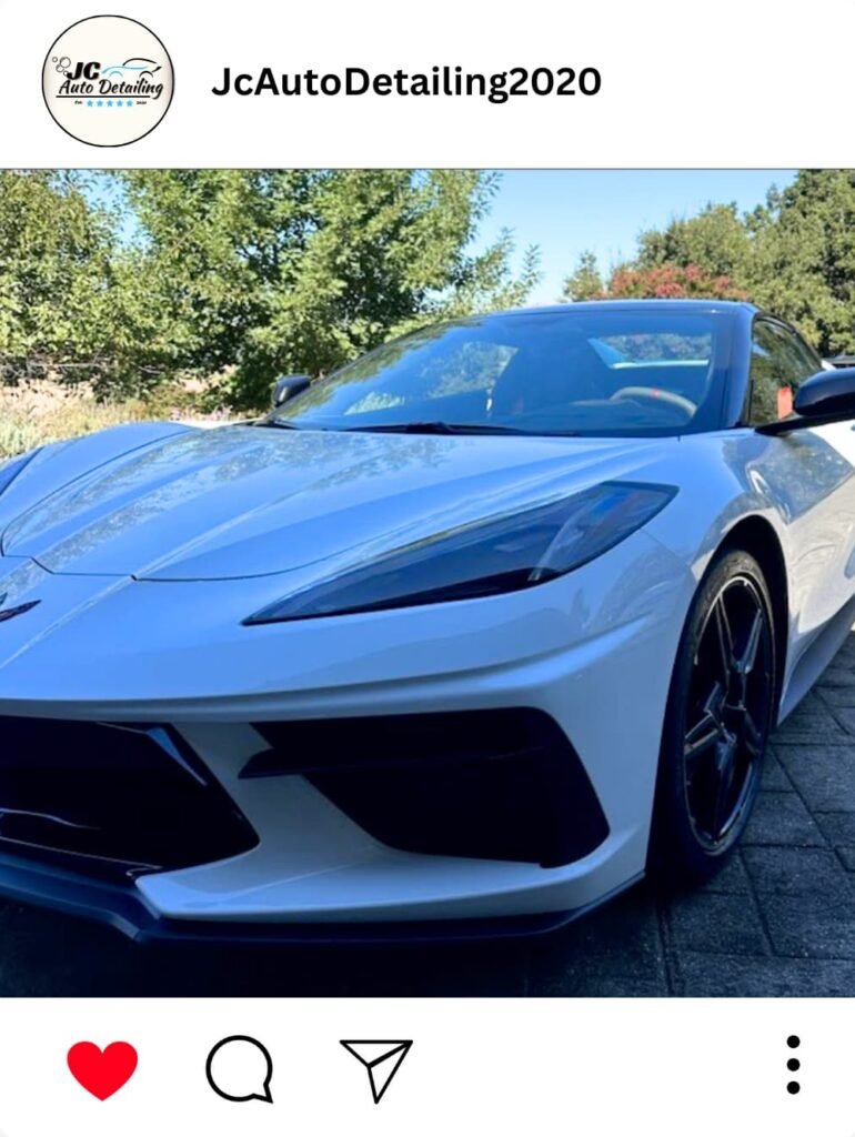 A white Chevrolet Corvette C8, recently detailed, parked in a driveway. The car has black wheels and a clean, shiny finish.