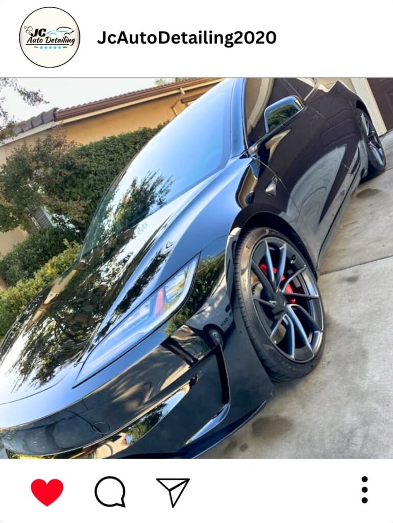 A black Tesla Model S, recently detailed, parked in a driveway. The car has black wheels with red brake calipers.